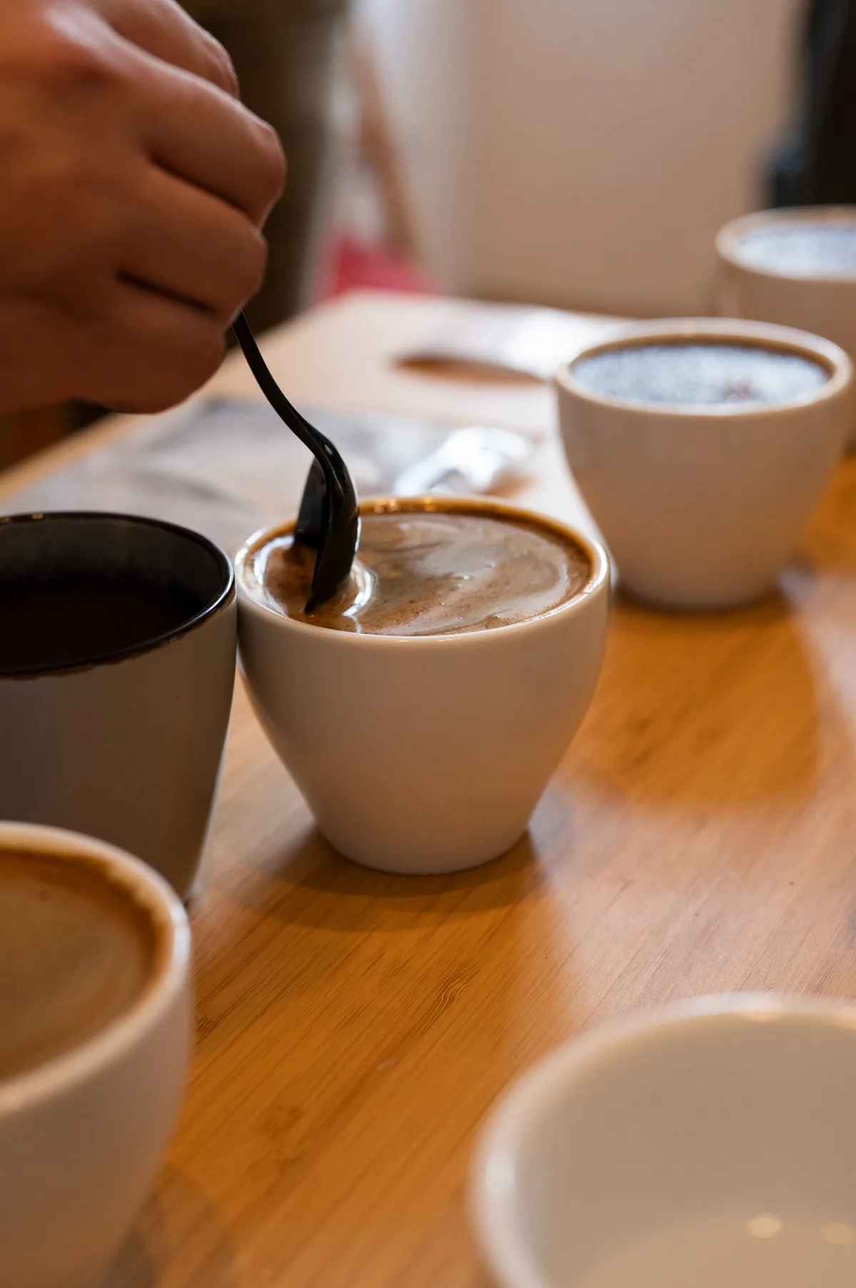 Con una cuchara se rompe la costra del café en una taza de catación